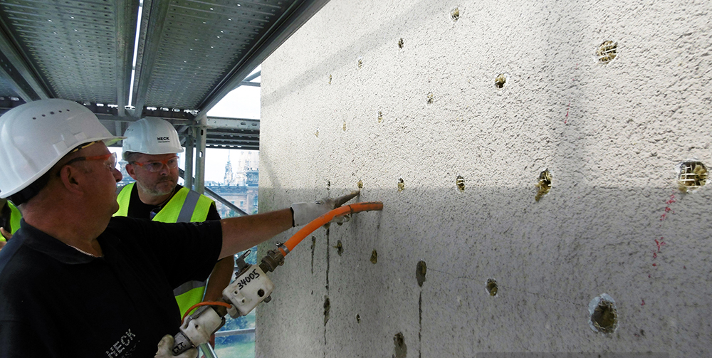 Bild: Heck Wall Systems Der Klebemörtel wird punktuell mittels Klebepistole zwischen Wand und Bestandsdämmung eingespritzt. Hierdurch entsteht eine dauerhafte Verbindung zwischen Untergrund und Alt-WDVS.